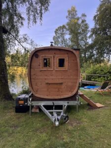 Mobil Hordó Kabin Szauna 86 A TimberIN Nordic Square mobil szauna elölnézete utánfutón egy tó mellett